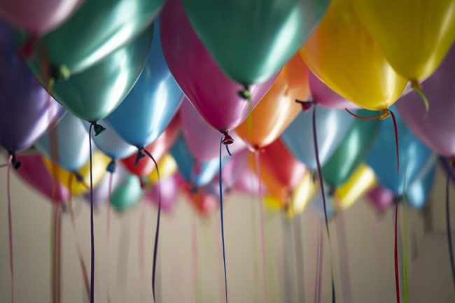 Multicolor balloons float to the ceiling.
