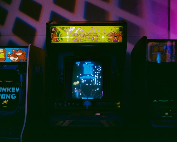 A few classic arcade games are lined up against the wall.