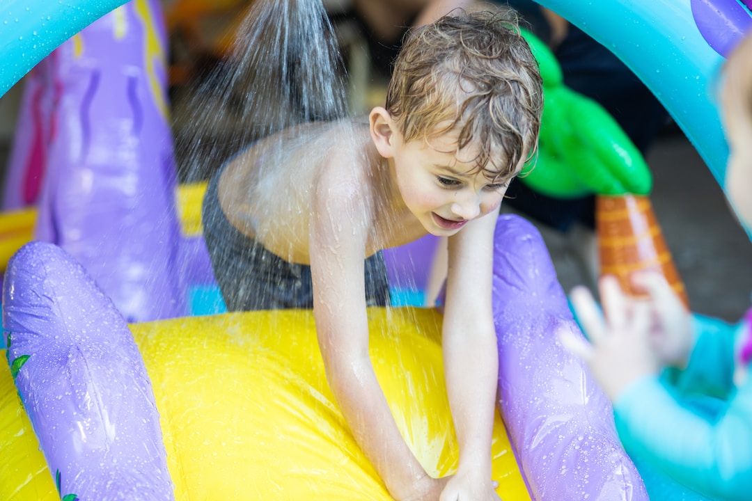 A small boy having fun on an inflatable water slide.