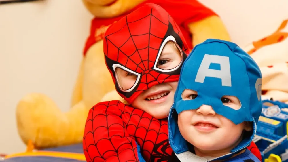 Two kids dressed up as superheroes for a birthday party, utilizing party rental services.