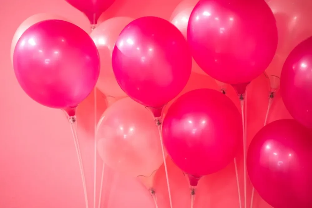Bright pink different-colored balloons against a pink background used for a party with party rentals.
