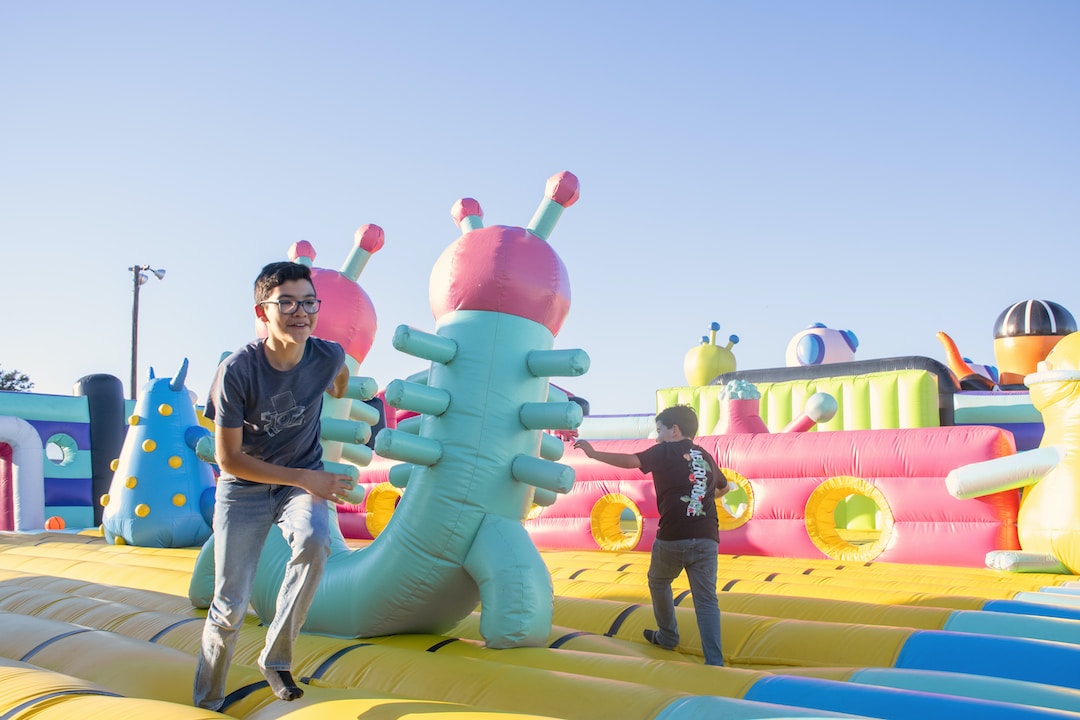 Two kids enjoying themselves on an inflatable obstacle course.